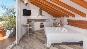 A modern bedroom with a large bed, a desk, and a kitchenette. - Apartamentos Al Andalusi (Dénia)