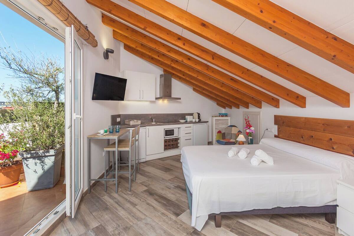Un dormitorio moderno con una cama grande, un escritorio y una kitchenette.
