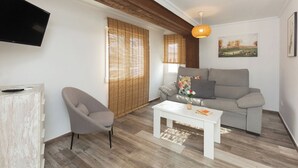 A modern living room with a grey sofa, a white coffee table, and a grey armchair. - Apartamentos Al Andalusi (Dénia)