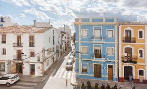 Vista de una calle con edificios, coches aparcados y un peatón.