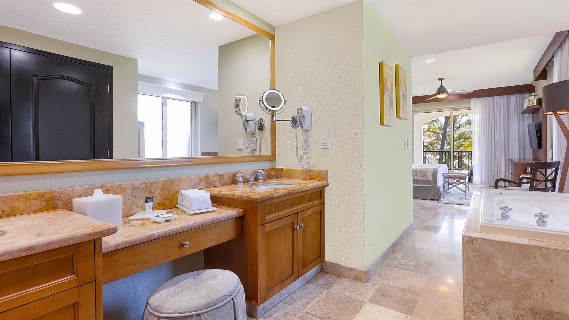 A bathroom with a marble countertop, wooden cabinets, a large mirror, and a bathtub.