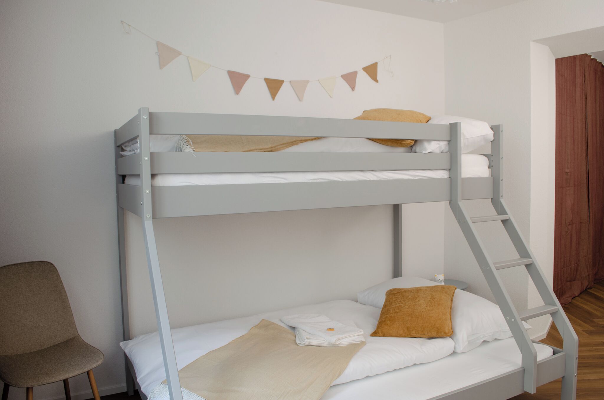 A bunk bed with a ladder, a chair, and a wall-mounted decoration.