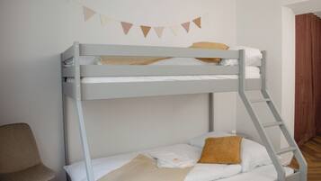 A bunk bed with a ladder, a chair, and a wall-mounted decoration.