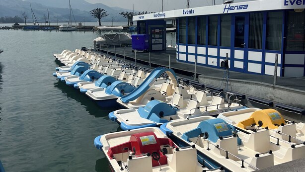 Un port de plaisance où plusieurs petits bateaux sont amarrés devant un bâtiment portant l’inscription « Hensa Events ».