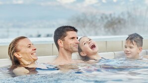 Une famille dans un jacuzzi, avec une chaîne de montagnes en arrière-plan.