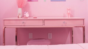 A pink-themed room with a desk, a vase with pink feathers, a pink alarm clock, and two wall art pieces. - Pink Mini Unit With Pool in Philly (Philadelphia)