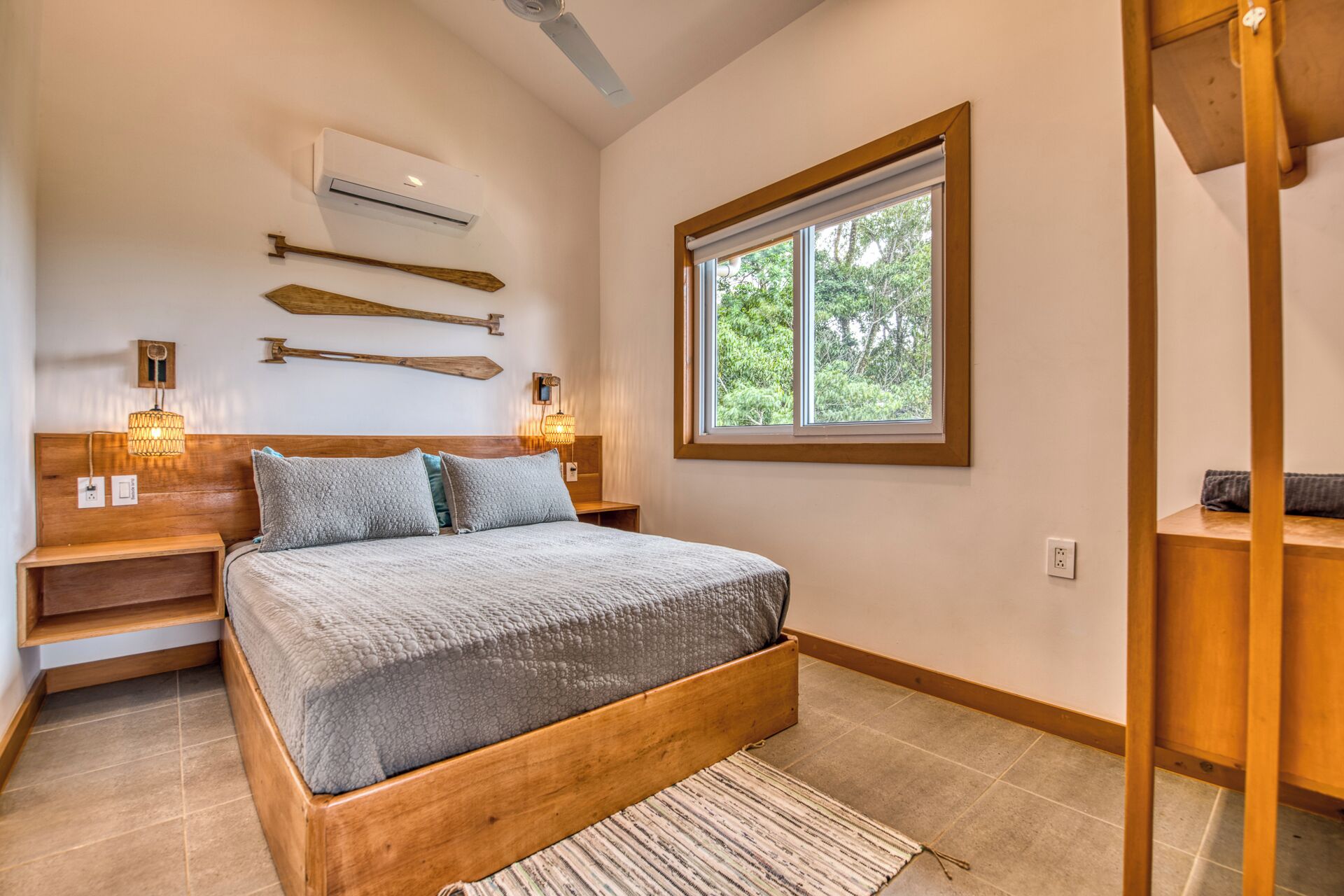 A bedroom with a bed, bedside lamps, a window, and a wooden headboard.
