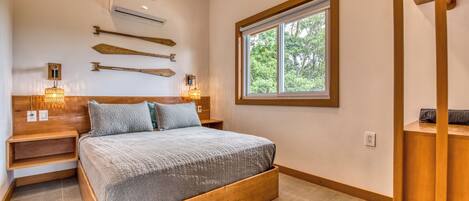 A bedroom with a bed, bedside lamps, a window, and a wooden headboard.