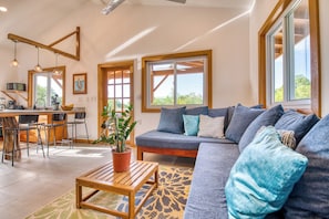 A spacious living area with a sofa, a coffee table, and a dining area with chairs.