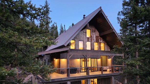 Une cabane en bois dotée d’un balcon, entourée d’arbres.