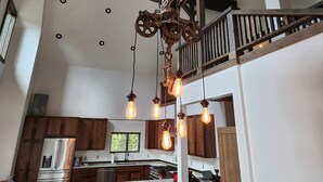 Une cuisine spacieuse avec des meubles en bois, un réfrigérateur en acier inoxydable et des luminaires suspendus.