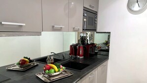 Una cocina moderna con encimera negra, electrodomésticos de acero inoxidable y un microondas sobre el fregadero.