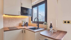 Cocina compacta con microondas, tetera y lavabo.