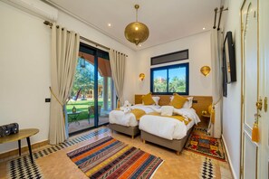 Ein Schlafzimmer mit zwei Betten, einem großen Fenster und Blick ins Freie.