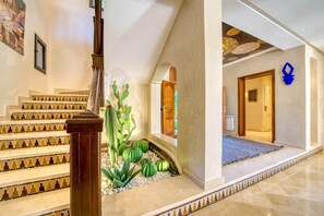 Eine Treppe mit gemusterten Stufen, eine Kakteepflanze und ein Durchgang zu einem weiteren Raum.