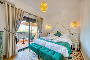 Ein Schlafzimmer mit Bett, einer Bank, einem Balkon und Blick ins Freie.