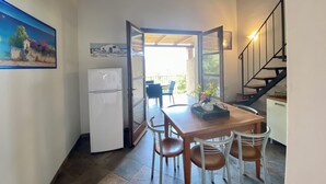 Ett kompakt kök med ett kylskåp, ett matbord med stolar och en trappa som leder upp till en övre våning.