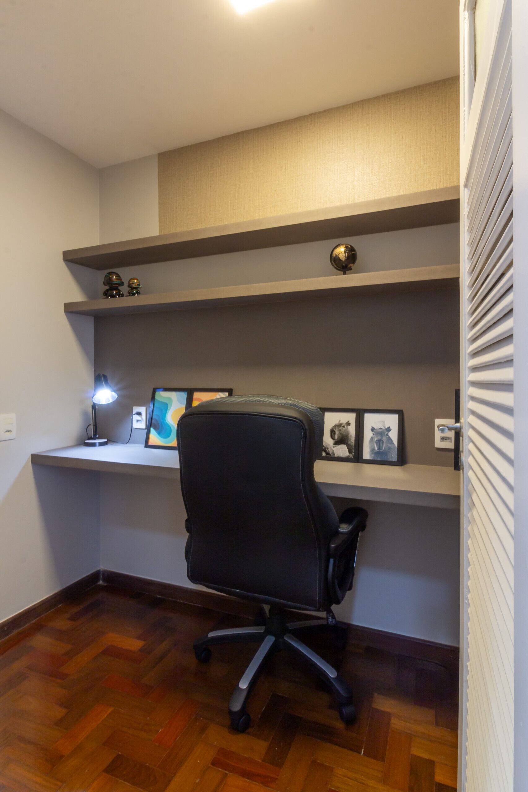 Oficina en esquina con escritorio, silla y estantería.