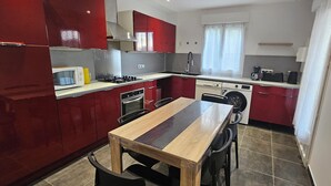 Ett kompakt kök med röda skåp, en mikrovågsugn, en spis och en tvättmaskin.