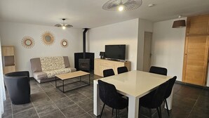 Ett modernt vardagsrum med en soffa, ett matbord med stolar, en TV och en öppen spis.