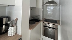 A compact kitchen with white cabinets, a stainless steel range hood, a built-in oven, and a coffee maker. - In the heart of Hardelot, 2 minutes' walk from the beach. Renovated 5-person apartment (Neufchâtel-Hardelot)