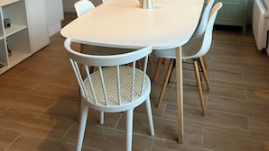 A modern kitchen with a white table, wicker chairs, and a hanging light fixture. - In the heart of Hardelot, 2 minutes' walk from the beach. Renovated 5-person apartment (Neufchâtel-Hardelot)