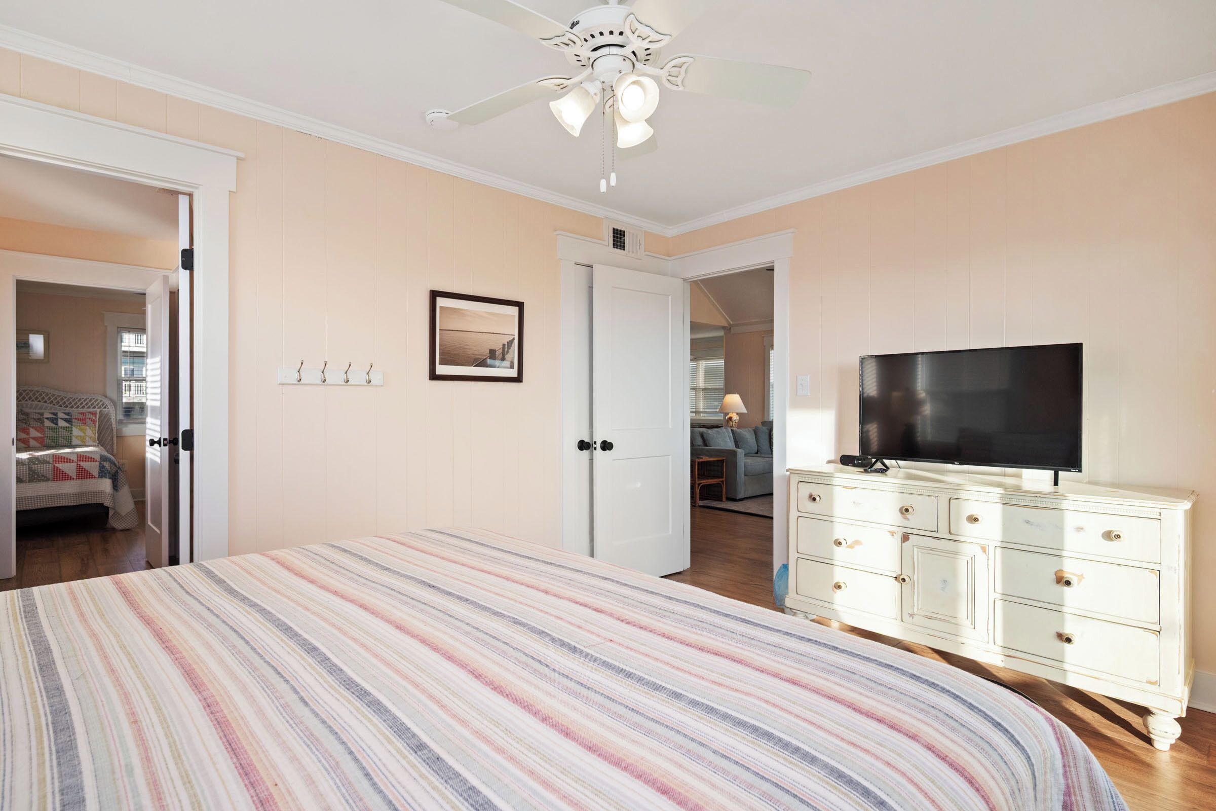 Une chambre à coucher comprenant un lit, un téléviseur, une commode et un ventilateur de plafond.