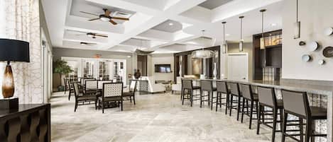 Une cuisine spacieuse avec un long bar, un design moderne au niveau du plafond et un coin repas comprenant une grande table et des chaises.