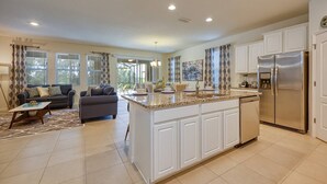A spacious kitchen with white cabinetry, a granite countertop, and a stainless steel refrigerator. - 6BR/6BA Private Pool Home in Solterra (Davenport)