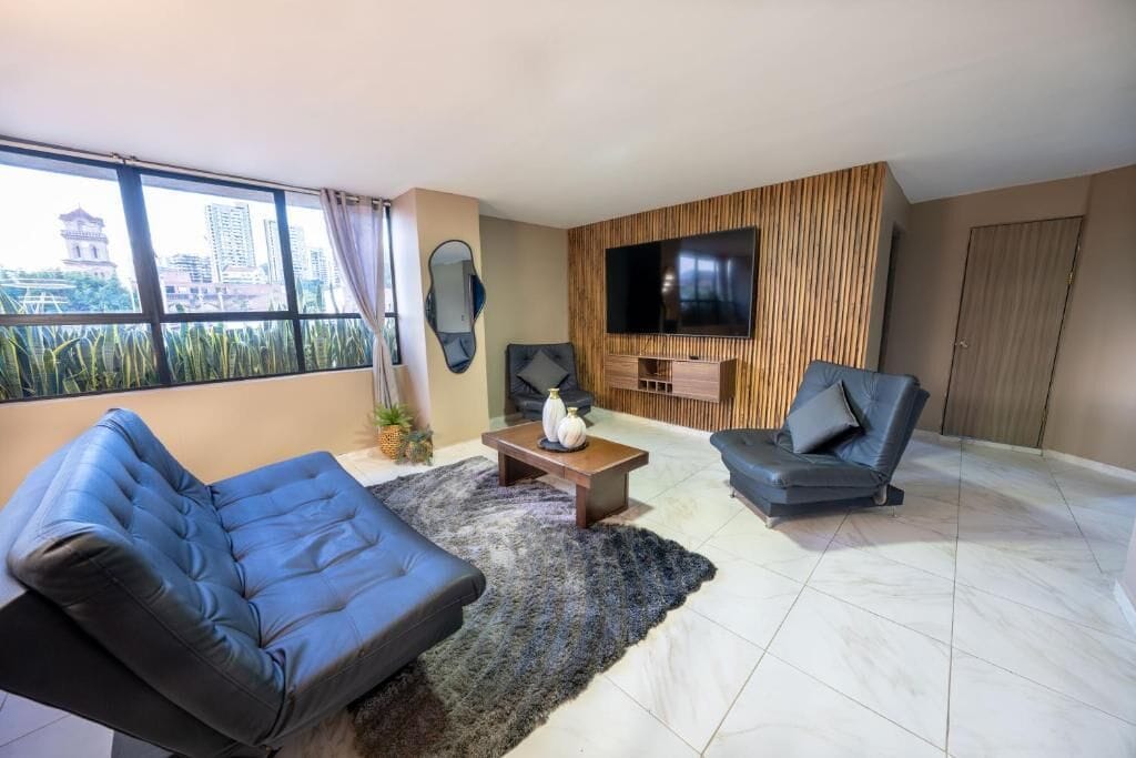 A modern living room with two sofas, a coffee table, and a TV mounted on the wall.