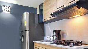 A modern kitchen with wooden cabinets, a stainless steel refrigerator, a gas stove, and a coffee maker. - 3BR  w Arcade 1 Block from Lleras Park (Medellín)