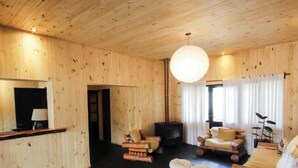 Una habitación con paneles de madera, un sofá, un televisor y una mesita con una lámpara.