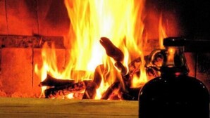 Fuego ardiendo en una chimenea con un recipiente metálico al frente.
