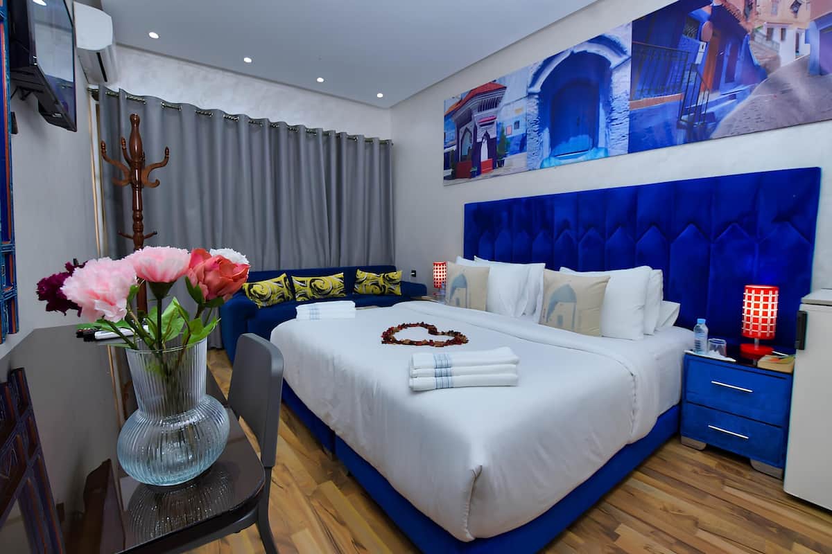Une chambre d’hôtel avec un grand lit, une table de chevet, un vase de fleurs et un tableau au mur.