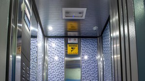 An elevator with a patterned wall and a sign indicating a smoking area. - Hotel Dar Annasr (Chefchaouen)
