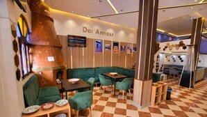 A cozy restaurant with green seating, a checkered floor, and a large tree-like structure on the left. - Hotel Dar Annasr (Chefchaouen)