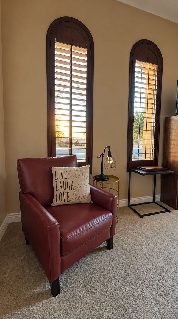 A room with a leather armchair, a small table with a lamp, and two arched windows with blinds. - Desert Ridge Casita with Private Entrance (Phoenix)