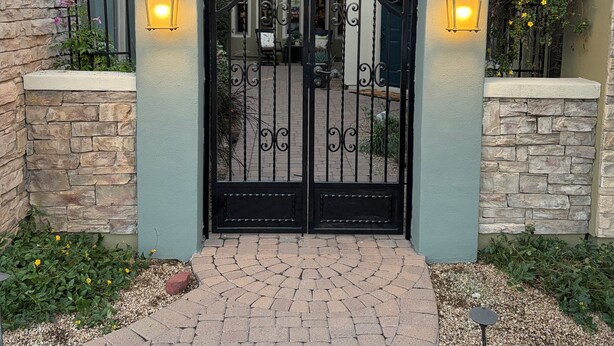 A gated entrance with a stone wall and a brick pathway leading to a building with a tiled roof. - Cozy Private Casita, Quiet & Comfortable (Phoenix)