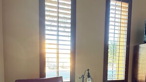 A living room with a leather armchair, a side table with a lamp, and two windows with blinds. - Cozy Private Casita, Quiet & Comfortable (Phoenix)