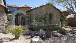 A house with a stone facade, a large arched entrance, and a well-maintained garden with various plants and rocks. - Cozy Private Casita, Quiet & Comfortable (Phoenix)