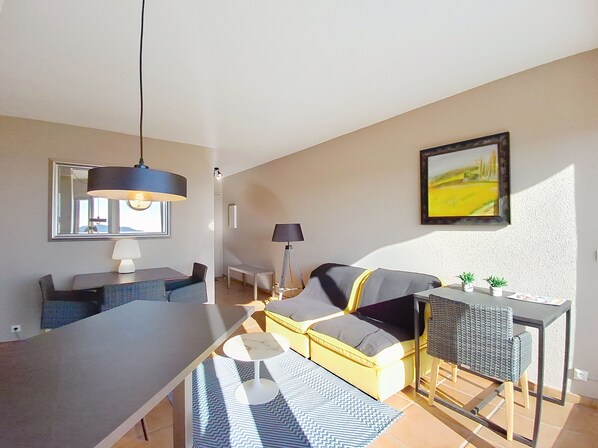 En moderne stue med sofa, spisebord og et køkkenområde.