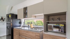 A modern kitchen with a built-in gas stove, a microwave, and a refrigerator. - 2BR w Pool Table 1 Block from Lleras (Medellín)