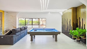 A modern indoor pool area with a pool table, seating, and large windows. - 2BR w Pool Table 1 Block from Lleras (Medellín)