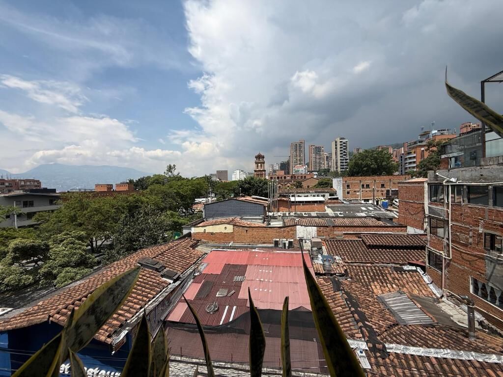 A rooftop view of a building with multiple terraces, some with red roofing and others with grey.