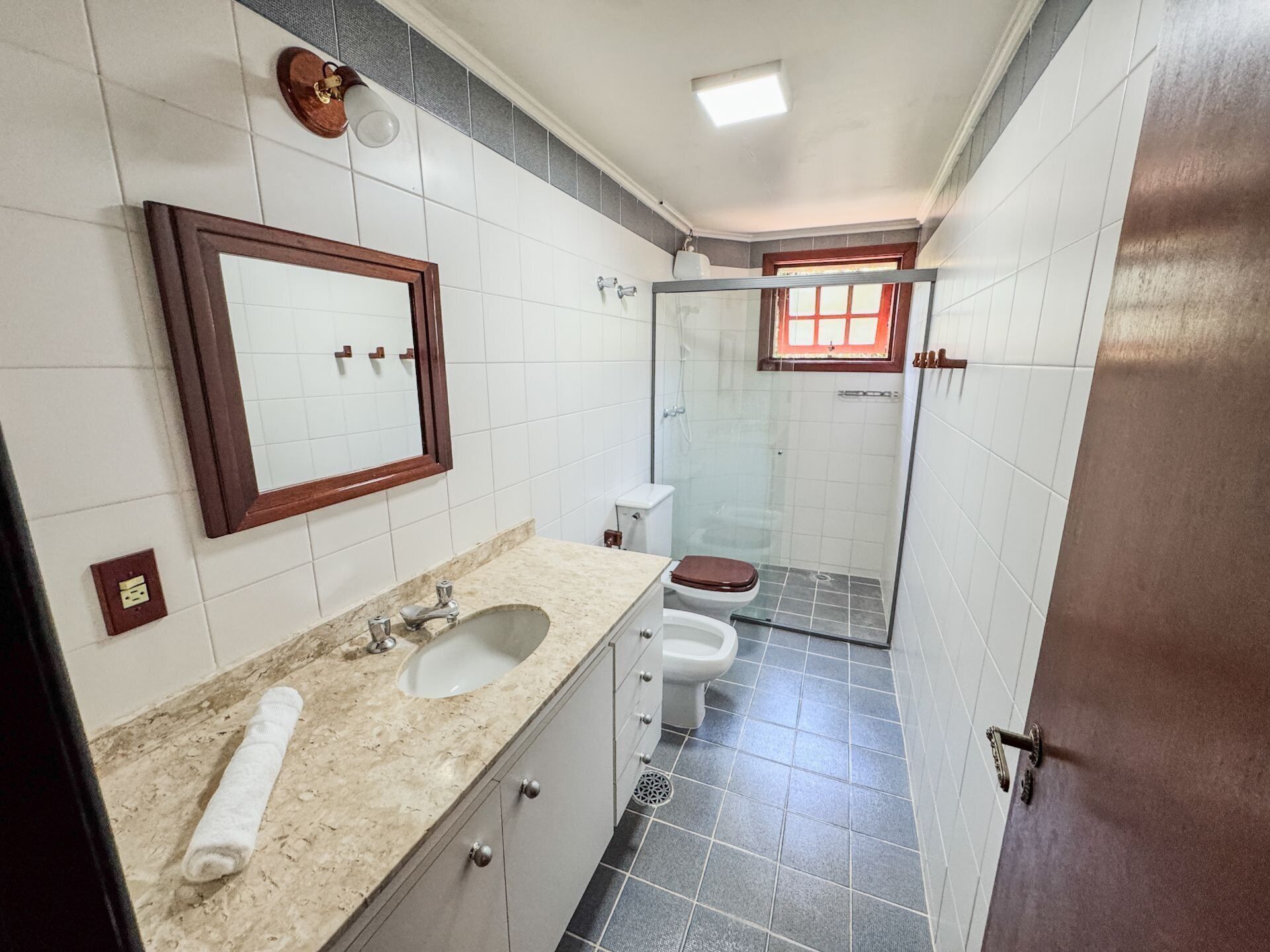 Une salle de bain équipée d’un lavabo, d’un miroir, de toilettes et d’une douche.