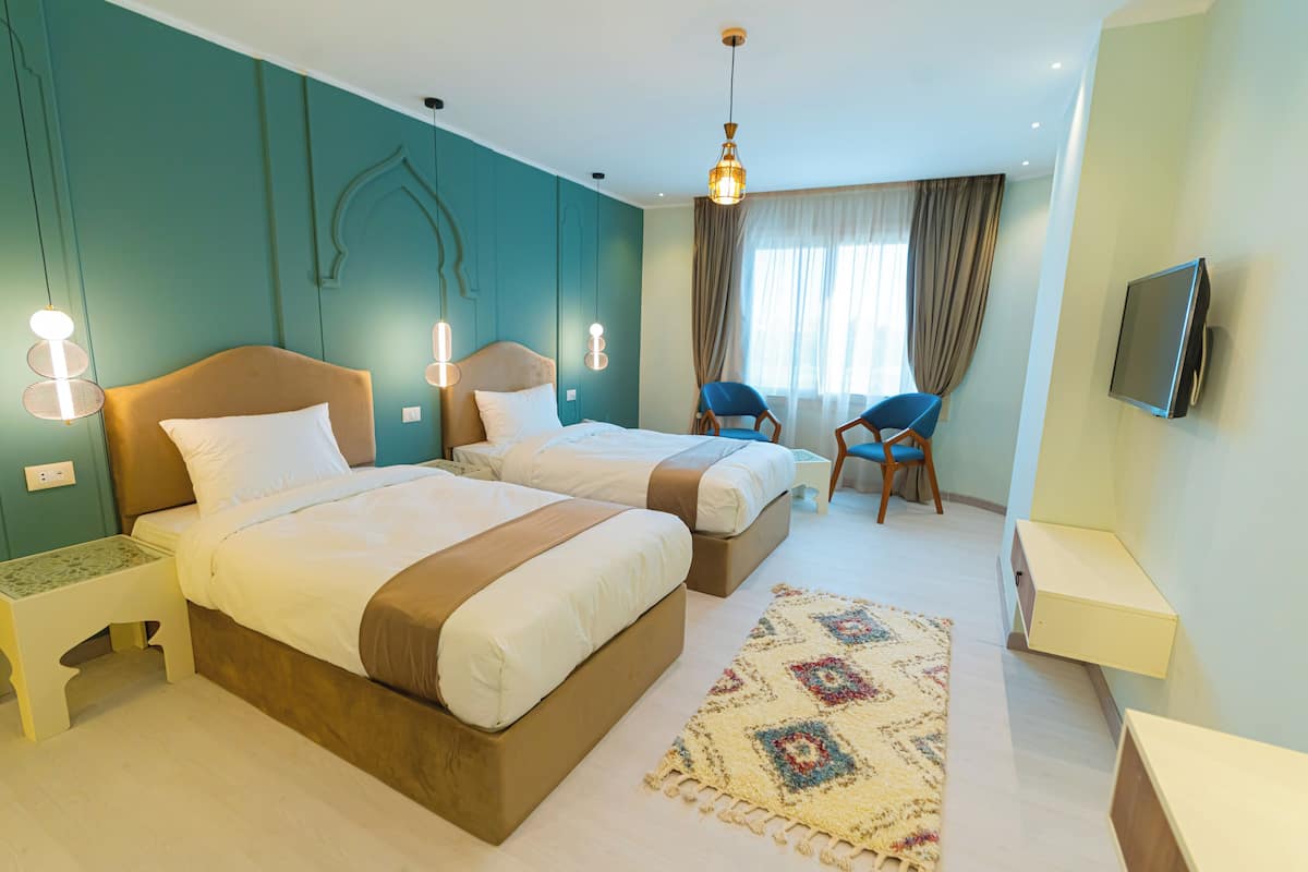 A hotel room with two beds, a television, a desk, and a chair.