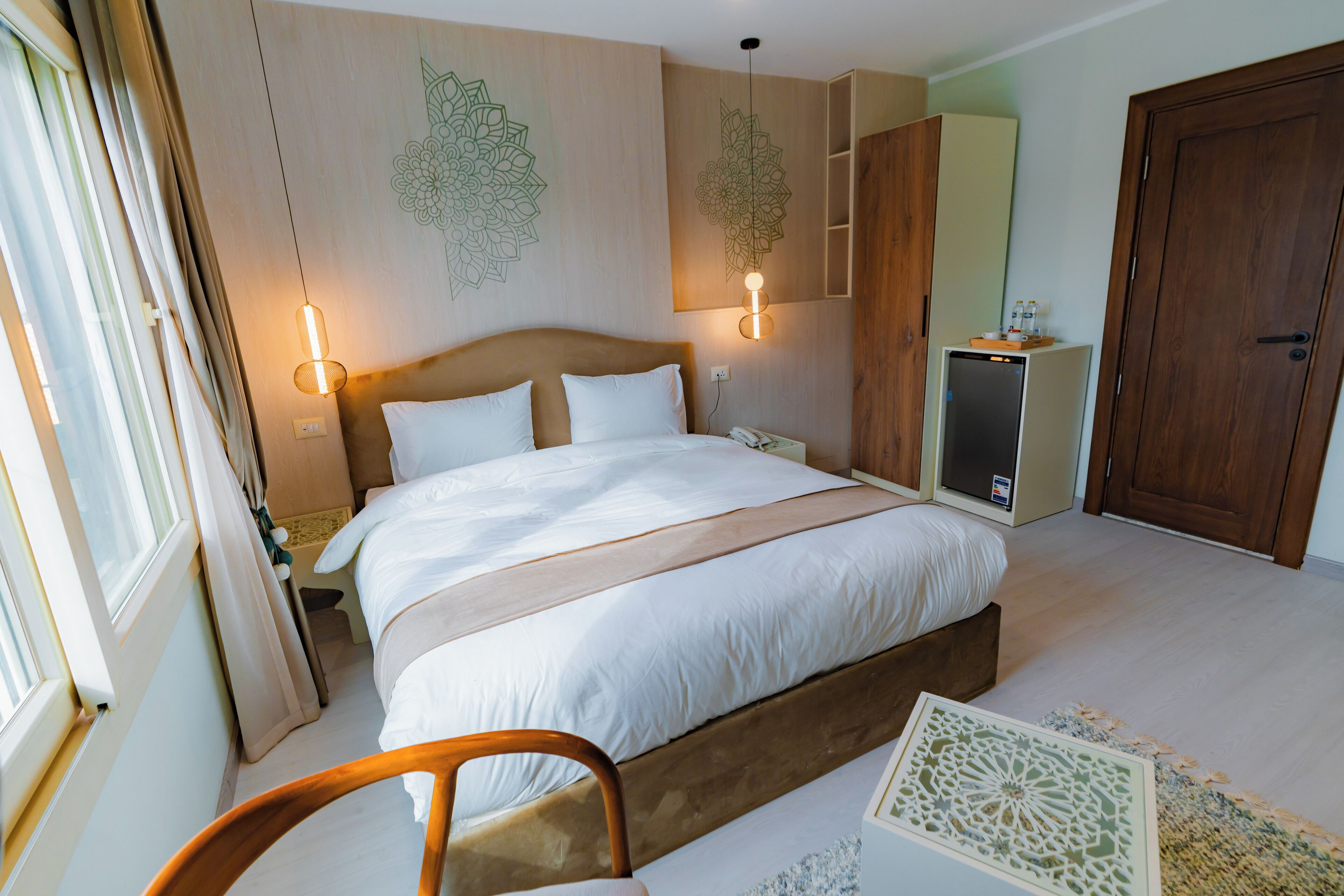 Une chambre à coucher bien aménagée, avec un grand lit, des lampes de chevet, une armoire en bois et un petit bureau avec une lampe.