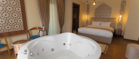 Ein modernes Hotelzimmer mit einer großen Badewanne, einem Bett mit weißen Leinen und dekorativen Wandpaneelen.