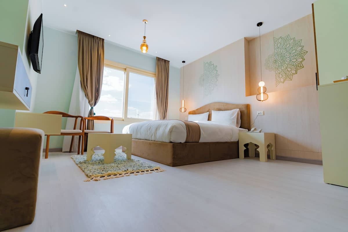 A modern hotel room with a large bed, a desk, and a TV.