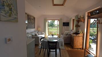 A cozy living room with a dining area, a television, and a view of the outdoors.